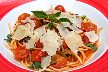 Spaghetti pasta with cherry tomatoes, parmesan cheese and herbs. Healthy vegan food concept, close up