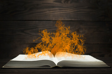 Open antique book Bible. On a wooden background. Fire from the book. Saint