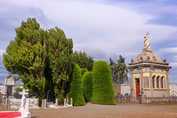 Cemetery of Punta Arenas, with beautiful green garden decoration, against a blue sky covered by white clouds.
