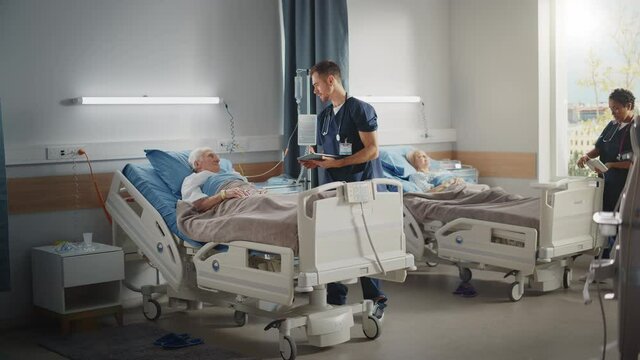 Hospital Ward: Friendly Male Nurse Talks Reassuringly to Elderly Patient Resting in Bed