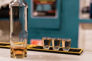 Tres vasos de chupito llenos con una bebida alcohólica oscura en la barra de un bar