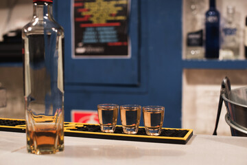 Tres vasos de chupito llenos con una bebida alcohólica oscura en la barra de un bar