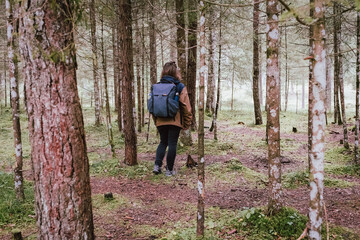 Small girl standing with her backpack in the middle of the forest in Germany