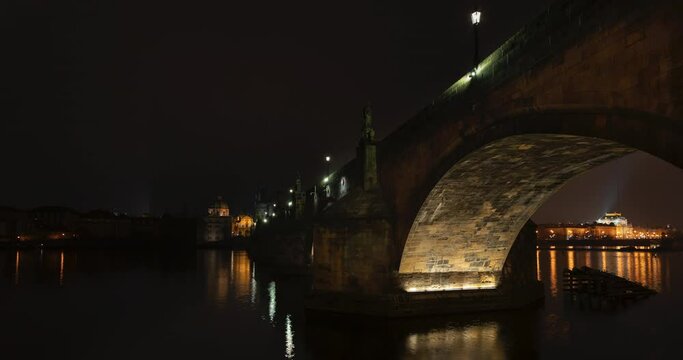 
time lapse flowing river vltava and stone charles bridge in cetro prague at night