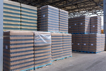 The open air storage and carriage of the finished product at industrial facility. A glass clear bottles for alcoholic or soft drinks beverages and canning jars stacked on pallets for forklift.