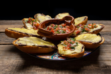 Mexican molletes with cheese and fresh sauce on wooden background