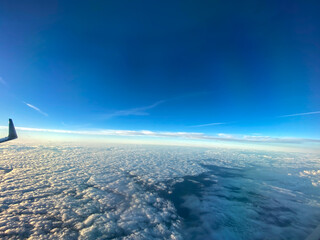 An aerial view from an airplane window of clouds with blue skies.