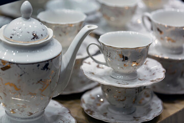 Set cups and teapot on a wooden table. Cups and saucers stacked on top of each other. A stack of mugs in shallow depth of field. empty mugs and saucers in restaurant for event celebration.