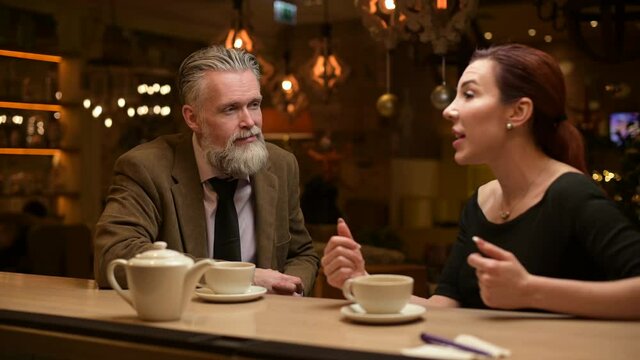 a man and a woman sit in a bar and chat on the eve of Christmas. A gray-haired man listens attentively to his interlocutor
