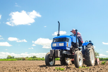 A farmer drives a tractor on a farm field. Bottom view. Loosening surface, land cultivation....