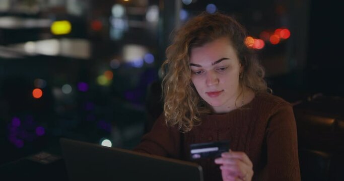 Attractive woman writes number of credit card into laptop, online banking