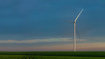 wind turbine in a green field in the hills of pure nature, eco-friendly electricity generation zero pollution on background blue sky with clouds, nobody.