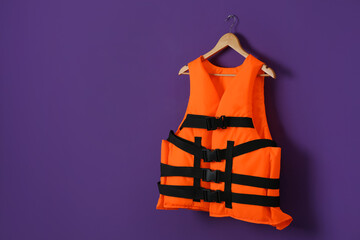 Orange life jacket on violet background. Space for text