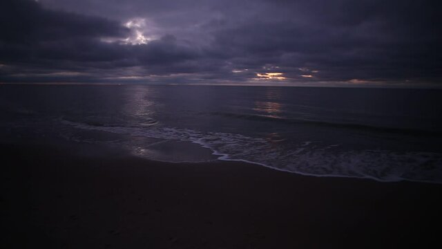 Cold winter windy Baltic sea coast beach in twilight purple light with dramatic cloudy sky and tranquil romantic waves. An HD video footage with audio