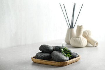 Spa stones and green leaf on light grey table. Space for text