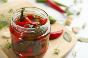 Glass jar of pickled chili peppers on table, closeup. Space for text