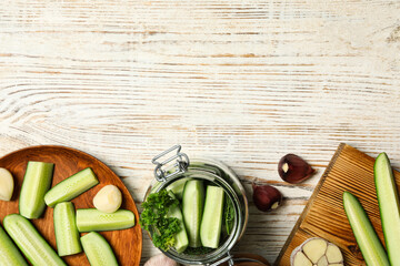 Pickling jar with fresh ripe cucumbers and spices on white wooden table, flat lay. Space for text