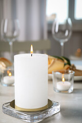 White burning wax candle on light table