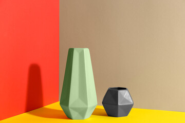 Stylish empty ceramic vases on color background