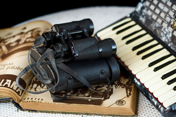 vintage binoculars over an antique book and an accordion