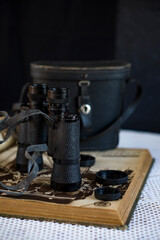 vintage binoculars on crocheted tablecloth and antique book