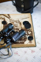 vintage binoculars on crocheted tablecloth and antique book
