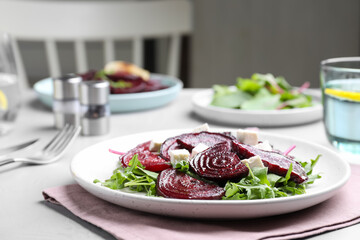 Roasted beetroot slices with feta cheese and arugula on light grey table