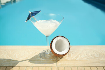 Tasty refreshing cocktail and coconut on edge of swimming pool. Party items