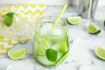 Delicious mojito and ingredients on white marble table