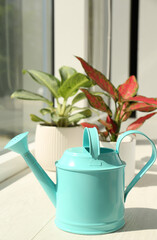 Different houseplants and watering pot on white window sill in room © New Africa