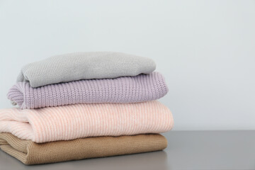 Fototapeta na wymiar Stack of folded warm knitted sweaters on grey table