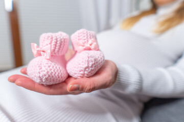 close up of a cute pregnant belly with baby shoes,in studio,on white background