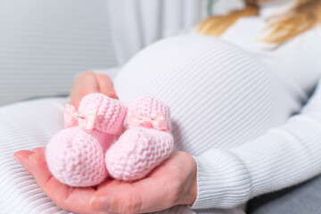 Small shoes for the unborn baby in the belly of pregnant woman. Pregnant woman holding small baby...