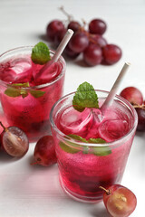Delicious grape soda water and berries on white table. Refreshing drink