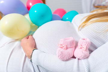 Pregnant woman tries to guess the boy or girl. Balloons as symbol of boy and girl. Gender of the unborn child concept. Copy space.