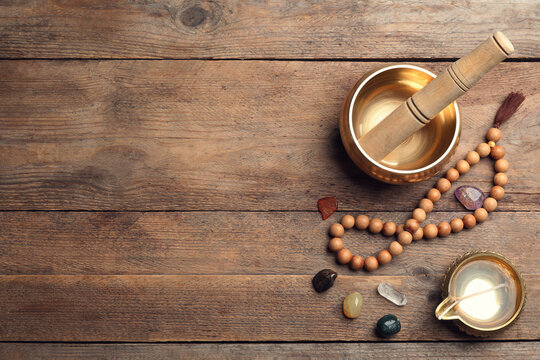 Flat lay composition with golden singing bowl on wooden table, space for text. Sound healing