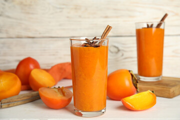 Tasty persimmon smoothie with anise and cinnamon on white wooden table