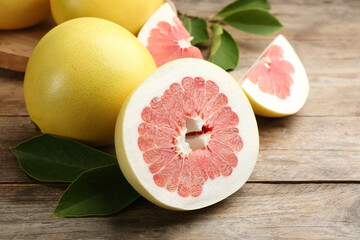 Fresh cut and whole pomelo fruits on wooden table, closeup