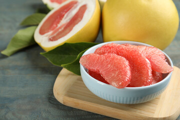 Peeled pomelo slices on blue wooden table, closeup