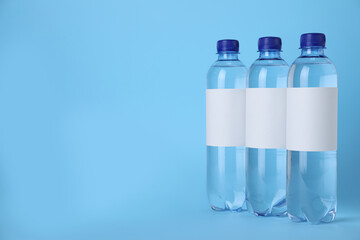 Plastic bottles with soda water on light blue background. Space for text