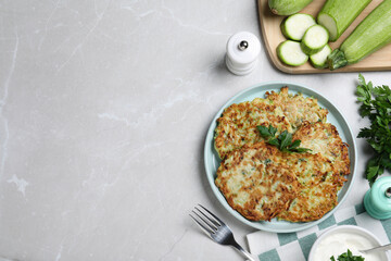 Delicious zucchini fritters served on light table, flat lay. Space for text