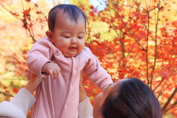 秋の紅葉と母親に抱っこされる赤ちゃん