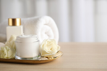 Spa composition with skin care products and flowers on wooden table. Space for text