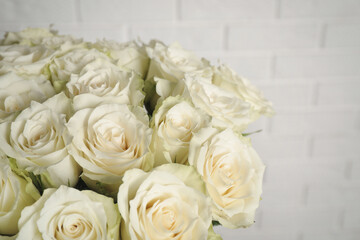 Luxury bouquet of fresh roses near white brick wall, closeup