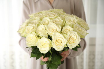 Woman holding luxury bouquet of fresh roses indoors, closeup