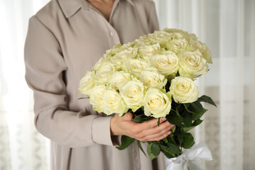 Obraz na płótnie Canvas Woman holding luxury bouquet of fresh roses indoors, closeup