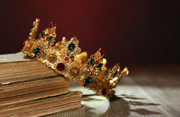 Beautiful golden crown and old books on wooden table. Fantasy item © New Africa