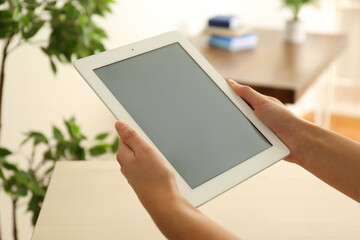 Young woman using new modern tablet indoors, closeup