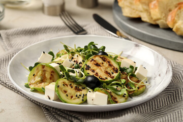 Delicious salad with grilled zucchini slices, feta cheese and olives on light grey table, closeup