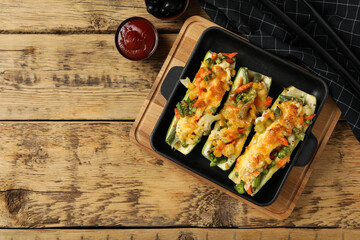 Baked stuffed zucchinis served on wooden table, flat lay. Space for text